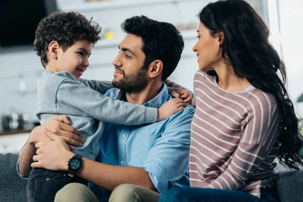 Happy latin father hugging cute son near wife at home — Stock Photo