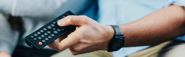 Cropped view of man holding remote control in hand — Stock Photo