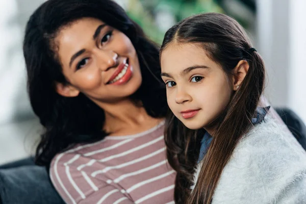 Femme latine et fille mignonne regardant la caméra à la maison — Photo de stock