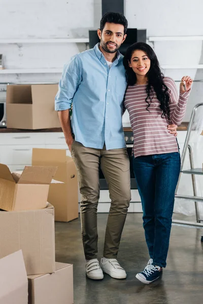 Cheerful latin woman holding keys from new home near husband — Stock Photo