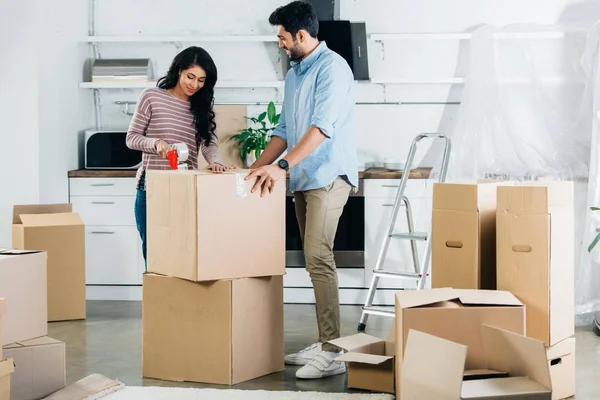 Joyeuses boîtes d'emballage couple latin tout en déménageant à la nouvelle maison — Photo de stock