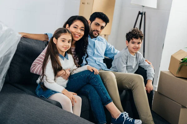 Feliz familia hispana sentada en un sofá en un nuevo hogar - foto de stock