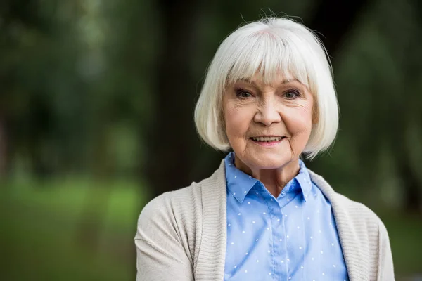 Donna anziana sorridente in camicia a pois blu — Foto stock