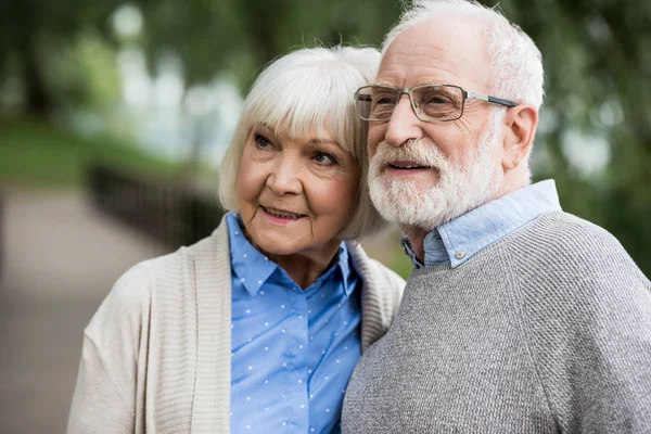 Feliz pareja de ancianos sonriendo y mirando hacia otro lado - foto de stock