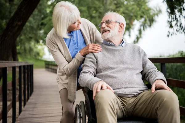 Гарна старша жінка з чоловіком у інвалідному візку в парку — стокове фото
