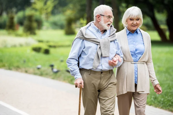 Feliz casal sênior falando enquanto caminhava no parque — Fotografia de Stock