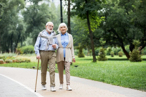 Happy stylish senior couple enjoying walking in park — Stock Photo