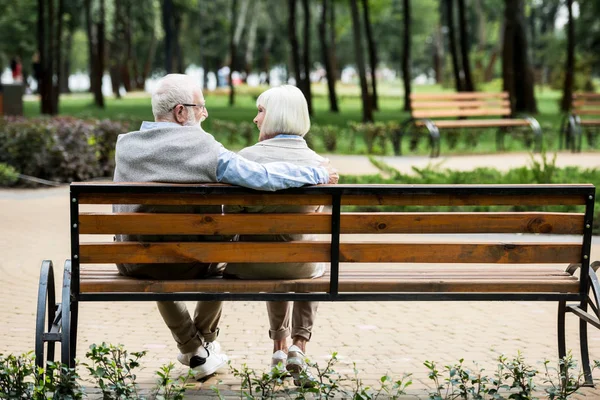 Casal sênior sentado no banco de madeira no parque — Fotografia de Stock