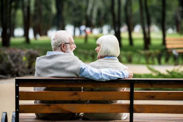 Feliz casal sênior descansando no banco de madeira no parque — Fotografia de Stock