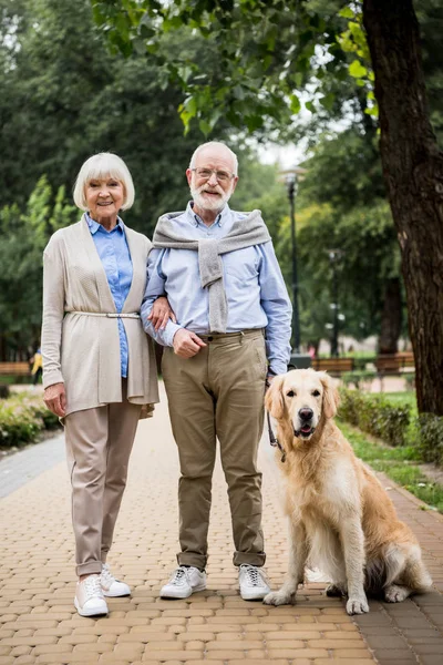 Happy smiling senior couple with adorable dog in park — Stock Photo