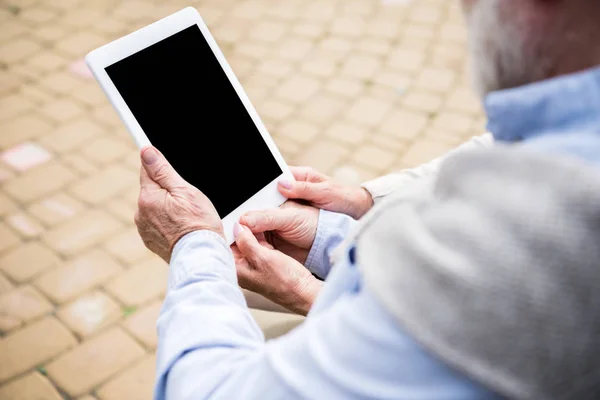 Pareja de ancianos usando tableta digital mientras están sentados juntos - foto de stock