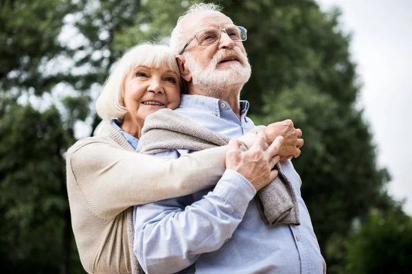 Felice coppia di anziani che abbraccia e sorride nel parco — Foto stock
