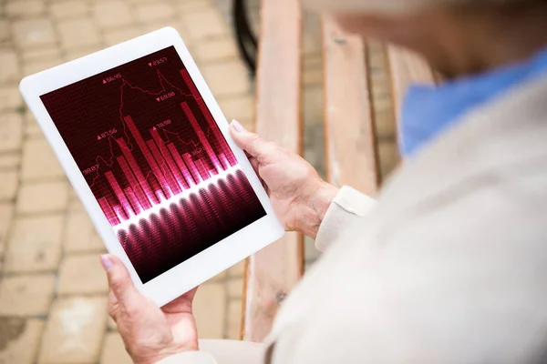 Foyer sélectif de la femme âgée tenant tablette numérique avec des cotes d'actions à l'écran — Photo de stock