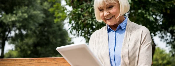 Smiling senior woman using digital laptop in park — Stock Photo