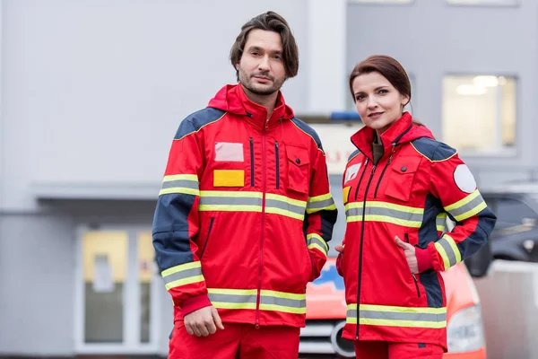 Paramédicos de uniforme vermelho em pé na rua e olhando para a câmera — Fotografia de Stock