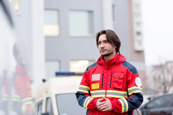 Ambulancier paramédical pensif en uniforme rouge debout dans la rue — Photo de stock