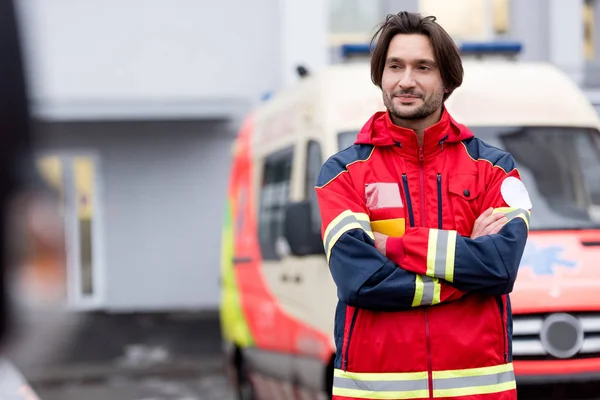 Ambulancier confiant en uniforme rouge debout dans la rue avec les bras croisés — Photo de stock