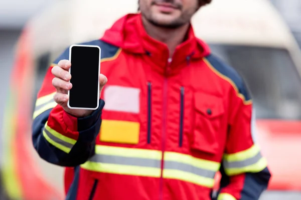 Vue recadrée de l'ambulancier paramédical en uniforme rouge tenant smartphone avec écran vide — Photo de stock