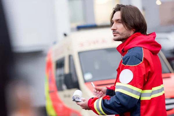 Pensive paramedic with clipboard looking away on street — Stock Photo