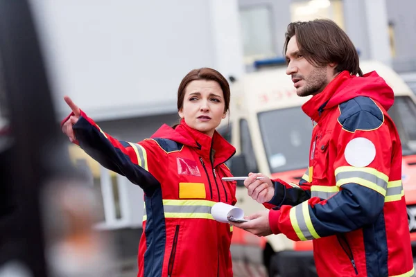 Paramedici con appunti e penna che parlano in strada — Foto stock