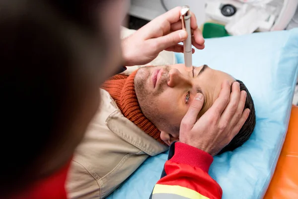 Vista cortada de paramédico fazendo exame ocular com paciente — Fotografia de Stock