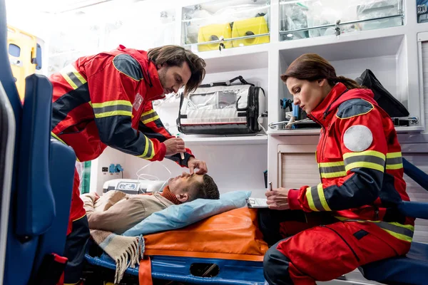 Paramedics doing eye examining in ambulance car — Stock Photo