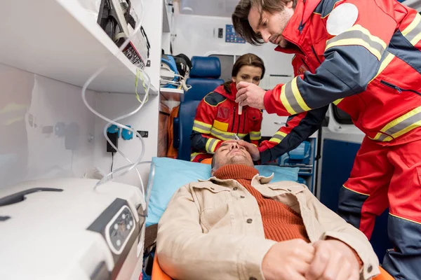 Paramedics doing eye examining in ambulance car — Stock Photo