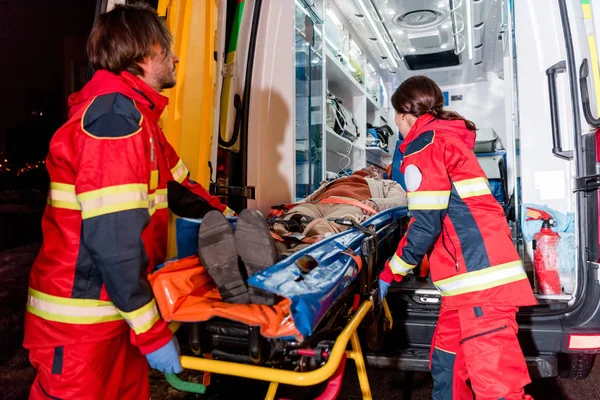 Paramedics transportating patient on gurney in ambulance car — Stock Photo