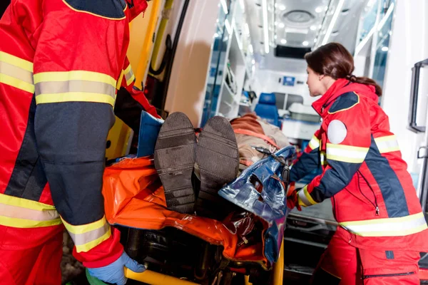 Paramedics transportating patient on gurney in ambulance car — Stock Photo