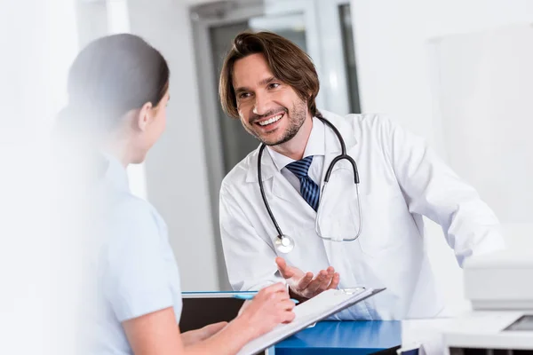 Lächelnder Arzt mit Stethoskop im Gespräch mit Krankenschwester — Stockfoto