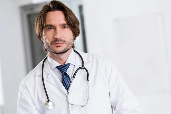 Seriöser Arzt mit Stethoskop blickt in Kamera — Stockfoto