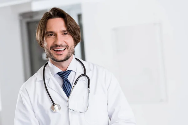 Médico excitado em casaco branco com estetoscópio olhando para a câmera — Fotografia de Stock