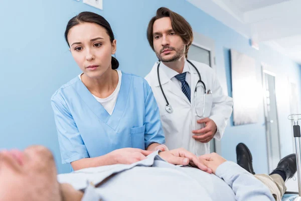 Medici preoccupati con stetoscopio guardando il paziente — Foto stock
