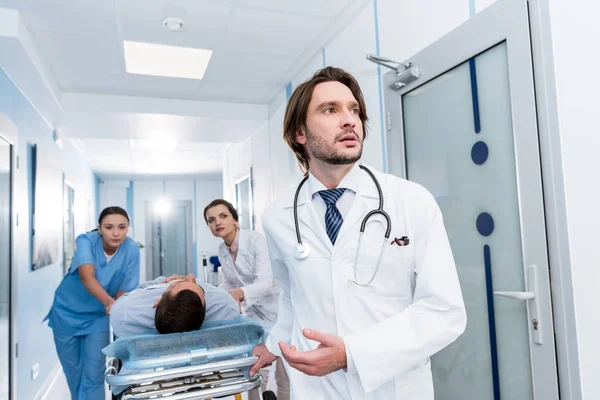 Médicos preocupados transportando al paciente al quirófano - foto de stock