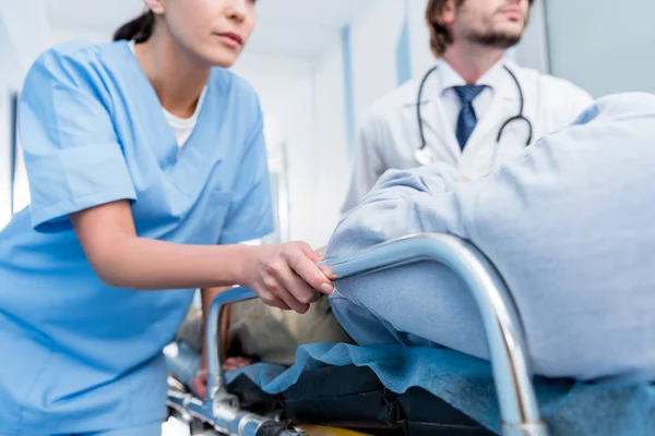 Cropped view of doctors in uniform transporting patient — Stock Photo