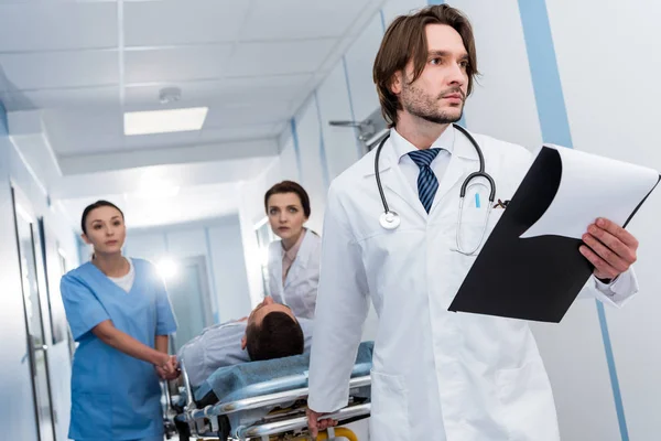 Doctors in uniform transporting patient on gurney — Stock Photo