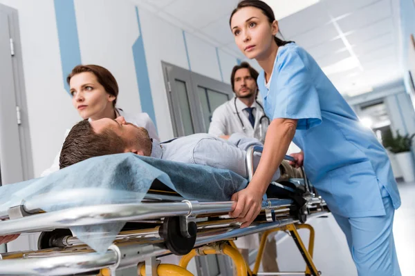 Doctors and nurse transporting unconscious patient on gurney — Stock Photo