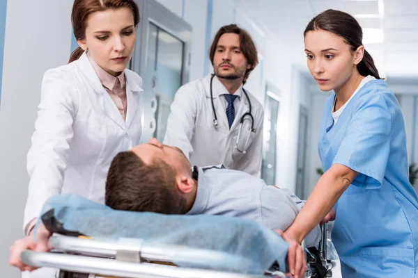 Doctors and nurse transporting unconscious patient on gurney — Stock Photo