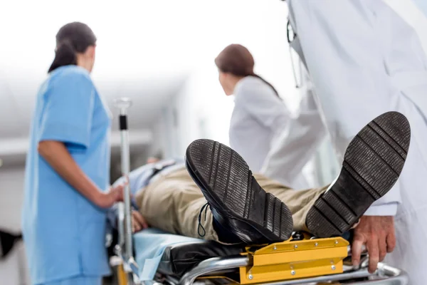 Doctors and nurse transporting unconscious patient on gurney — Stock Photo