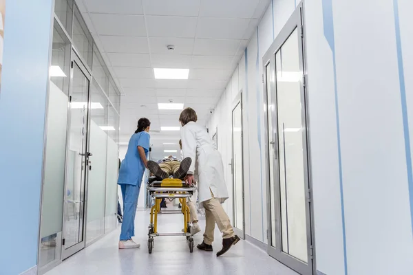 Лікарі та медсестра перевозять несвідомого пацієнта на Ґурні — стокове фото