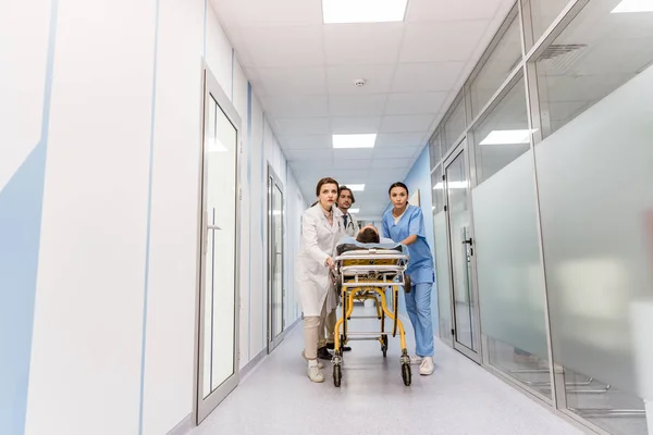 Médicos e enfermeiros transportando paciente inconsciente na maca — Fotografia de Stock