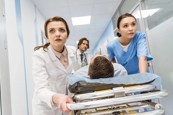 Médicos e enfermeiros transportando paciente inconsciente na maca — Fotografia de Stock