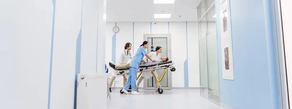 Концентрированные врачи и медсестра перевозят пациента без сознания на каталке — стоковое фото