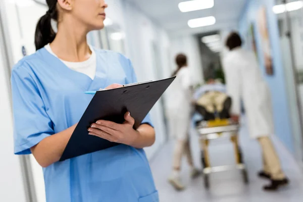 Cropped view of nurse in blue uniform holding clipboard — Stock Photo