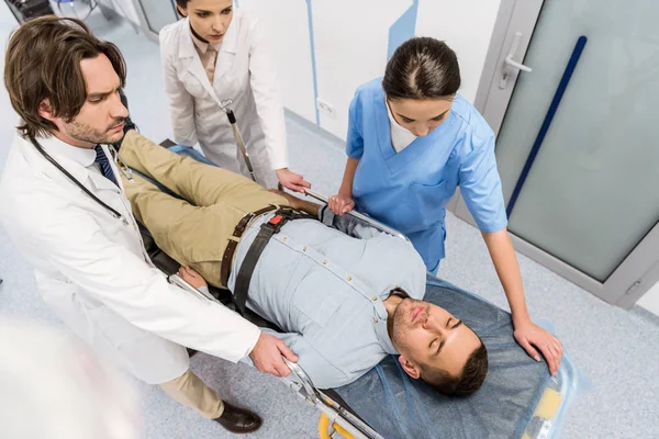 Cropped view of doctors transportating patient on gurney — Stock Photo