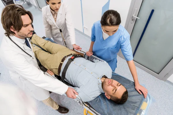 Ausgeschnittene Ansicht von Ärzten, die Patienten auf Gurney transportieren — Stockfoto