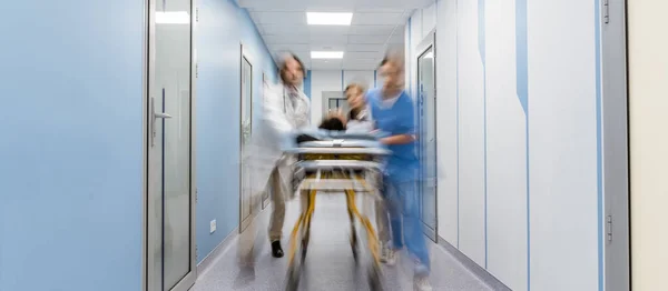 Groupe de médecins transportant le patient sur le brancard — Photo de stock