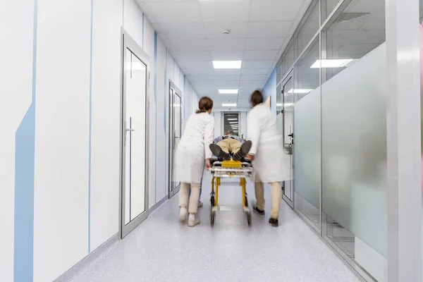 Groupe de médecins transportant le patient sur le brancard — Photo de stock