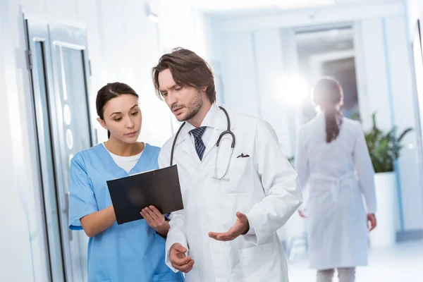 Enfermera con portapapeles mostrando notas al médico - foto de stock