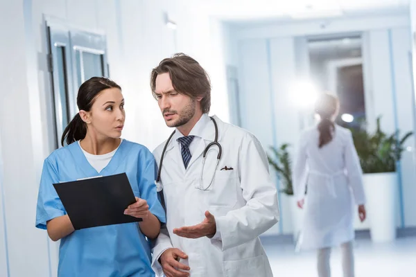 Médico concentrado discutiendo diagnóstico con enfermera en clínica - foto de stock